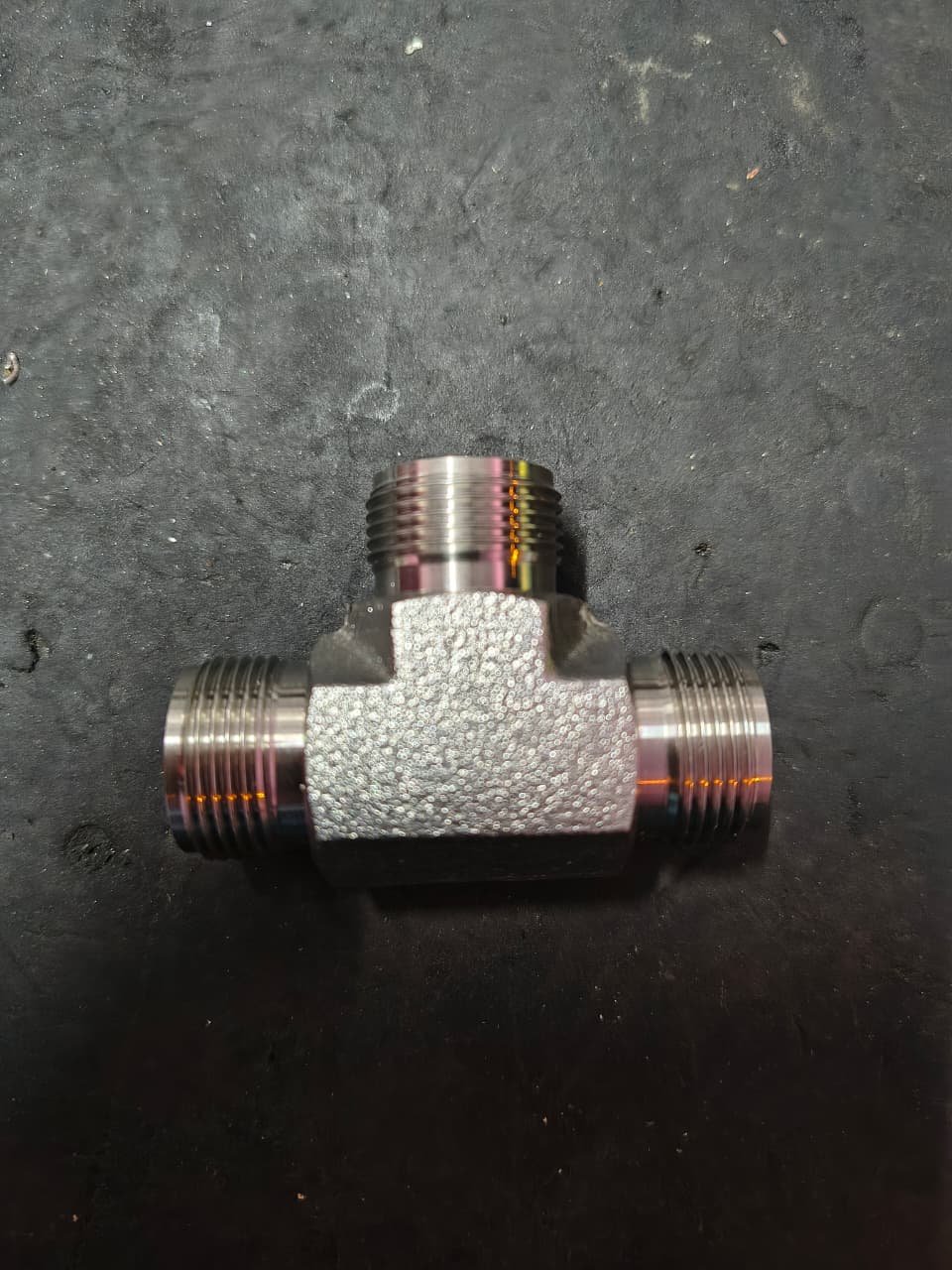 Three-way threaded steel tee fitting photographed from the front